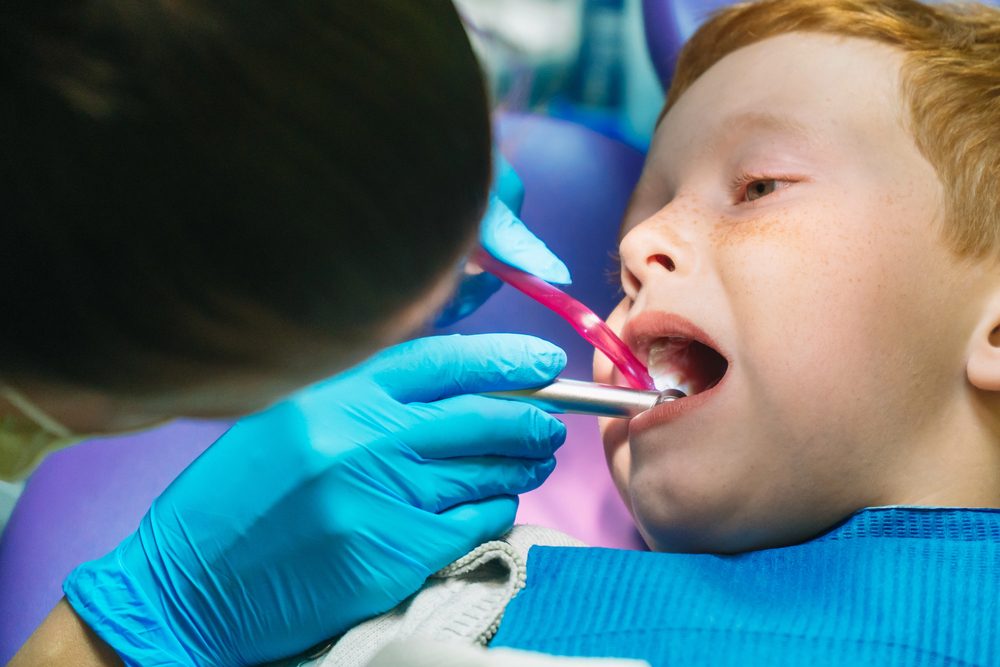 Scared red-haired boy crying at reception at dentist in dental chair
